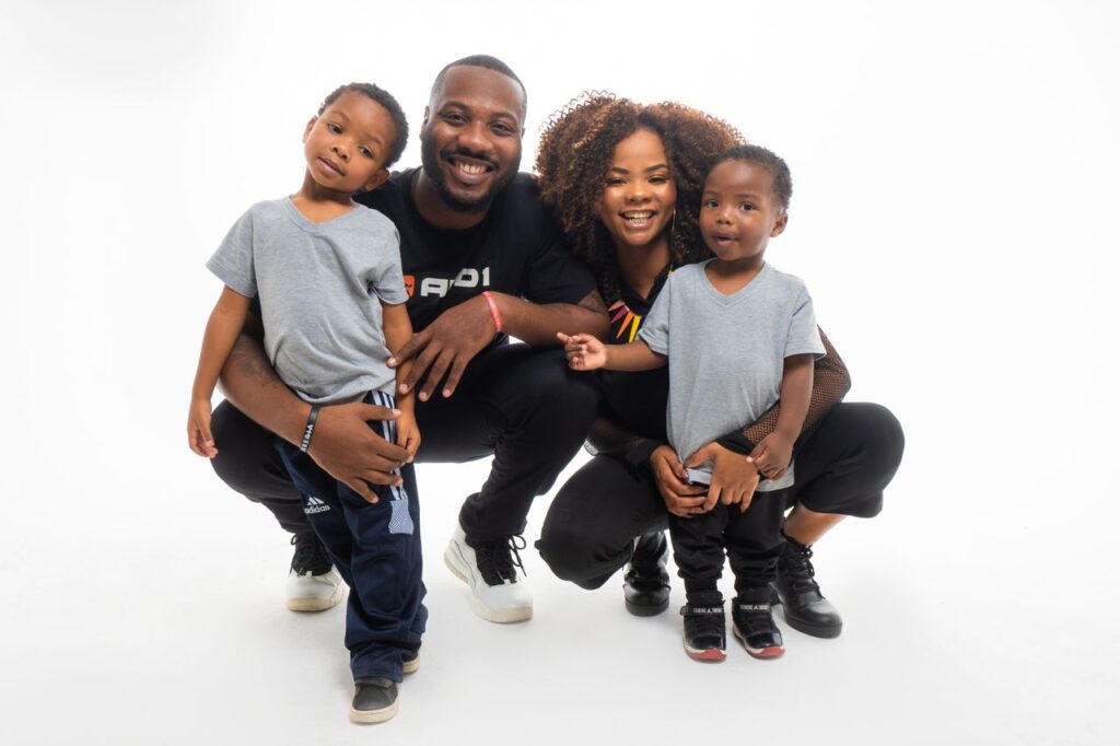 A joyful family with two children smiling against a white backdrop.