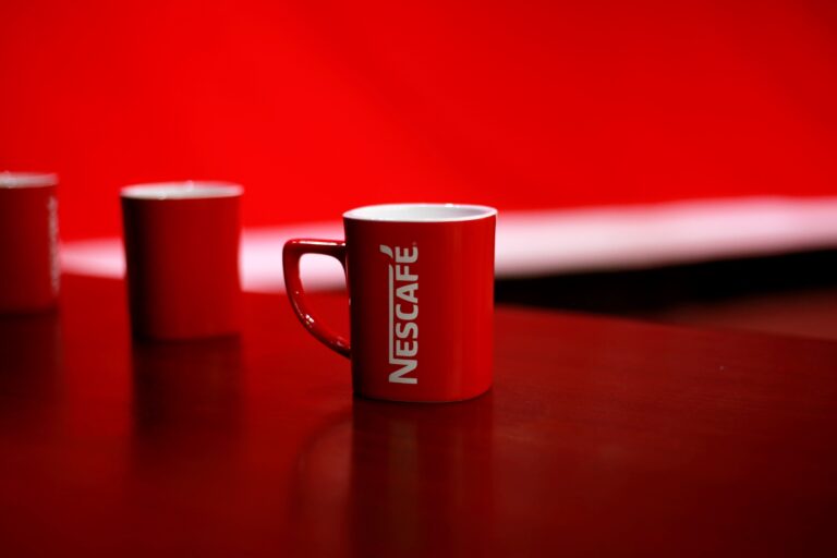 Bright red coffee mug featuring bold branding on a clean studio background.
